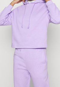 Ljuslila kort hoodie med snoddar, mjukt tyg, tillsammans med matchande sweatpants. Enkelt mönster med en avslappnad passform.