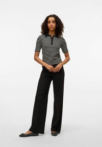 Black and white striped polo shirt with a collar, paired with black wide-leg pants and textured black flats. Smooth fabric with short sleeves.