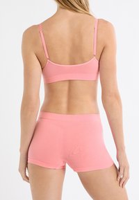 Set intimo rosa senza cuciture composto da reggiseno e short boyshort. Presenta spalline regolabili, tessuto morbido e finitura liscia. Entrambi i capi hanno un design aderente.