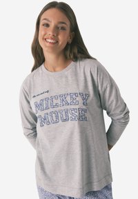 Grå langærmet skjorte med "MICKEY MOUSE" i blå mønstrede bogstaver, rund halsudskæring og afslappet pasform. Bæres med matchende mønstrede bukser.