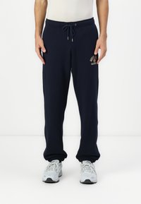 Mørkeblå sweatpants med elastisk talje, sn�ørre lukning og tapered manchetter. Har et frontlogo i lyse farver.