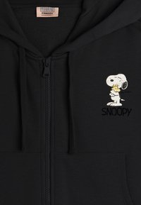 Felpa nera con zip realizzata in tessuto morbido, caratterizzata da una grafica del cartone animato Snoopy e il testo ricamato "SNOOPY" sull'area sinistra del petto.