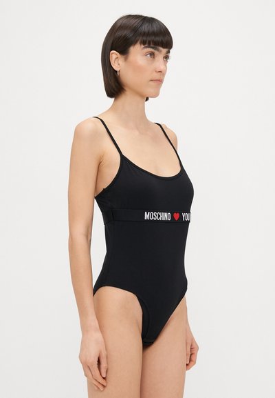 Crni jednodijelni kupaći kostim s tankim bretelama, s bijelim natpisom "MOSCHINO ❤️ YOU" na traku oko struka. Glatka tkanina, prilagođen kroj.
