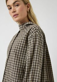 Skjorte med krave i ternet mønster, med beige og mørkeblå toner, vævet stof, synlig knapstolpe og design med sænket skulder.