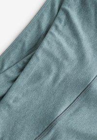 Blauwe sportstof met een gladde textuur en lichte glans, met zichtbare stiksels langs de randen en plooien in het materiaal.