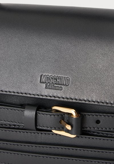 Sac noir en cuir Moschino Milano avec boucle dorée et surface texturée, vue rapprochée.