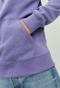 Felpa viola con cappuccio, dotata di polsini e orlo a coste, caratterizzata da una tasca a marsupio sul davanti, realizzata in tessuto morbido e strutturato.