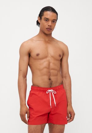 Shorts de bain rouges avec une finition mate, taille élastique et cordon blanc. Comprend un petit logo brodé sur l'ourlet inférieur.