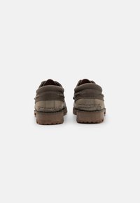 Braune Canvas-Schuhe mit einem Seilakzent, runder Spitz, dicker Gummisohle und einer strukturierten Oberfläche für bessere Griffigkeit. Ansicht von hinten.
