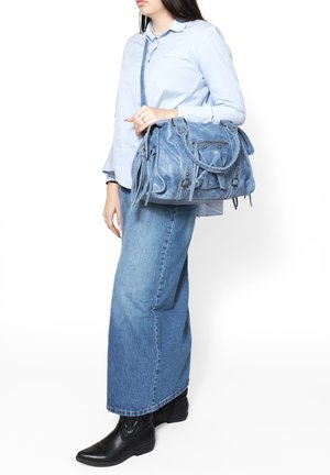 Borsa in denim di colore azzurro chiaro, con doppi manici superiori, tracolla regolabile, chiusura con zip e dettagli in frange.