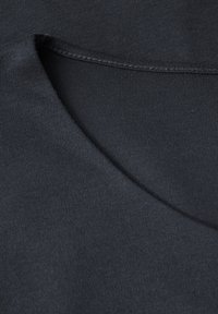Tissu en coton noir avec une texture lisse, présentant une encolure ronde et des coutures visibles le long des bords.