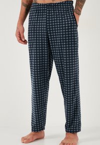 Tamno plave karirane lounge hlače s elastičnim pojasom, ravnog kroja i bočnim džepovima. Tkanina ima mekan i teksturiran osjećaj.