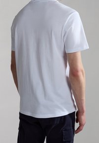 White cotton t-shirt viewed from the back, featuring a crew neckline, short sleeves, and a smooth texture. Fabric is plain without patterns.