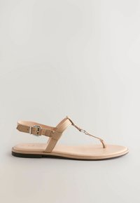 Beige matala sandaali yksinkertaisella muotoilulla. Varustettu T-nauhoilla, joissa on metallinen yksityiskohta ja nilkkahihnalla, jossa on solki. Sileä pinta.