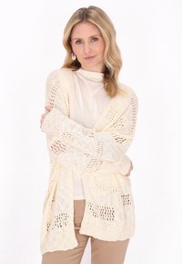 Cardigan a maglia aperta con maniche lunghe in crema, dal design morbido, caratterizzato da un motivo testurizzato e polsini a coste.