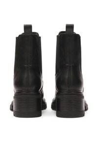 Botas de tobillo de cuero negro con paneles laterales elásticos, tacón texturizado y detalle de lengüeta para facilitar su uso. Diseño de punta cuadrada y tacón apilado.