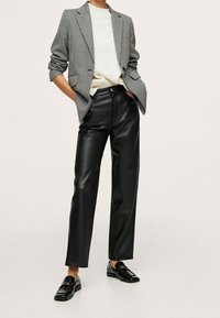 Czarne spodnie z ekoskóry w połączeniu z marynarką w wzór pepitki oraz kremowym, dzianinowym swetrem. Matowe wykończenia i dopasowany krój.