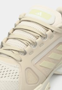 Heledat beežid spordijalatsid, millel on võrkmaterjalist pealmine osa, tekstuursete detailidega ja kolm kuuluvat triipu veidi tumedamas toonis. Tugevdustega keel ja paelad.