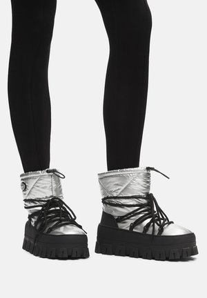 Srebrne pikowane botki za kostkę z czarną podeszwą, czarnymi sznurówkami i masywną platformą.
