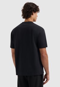 Zwarte t-shirt met korte mouwen van een zachte stof, met een subtiele logodetail aan de achterkant van de hals en een ontspannen pasvorm voor comfort.