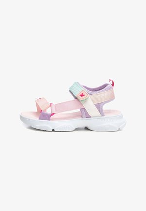 Sandalias infantiles coloridas con tiras moradas, rosas y menta, cierres ajustables de velcro y suela blanca de goma con dibujo texturizado.