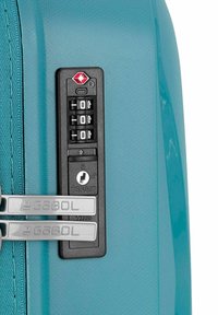 Maleta dura en color teal con un candado de combinación aprobado por la TSA en negro, herrajes plateados y superficie texturizada para un mejor agarre.