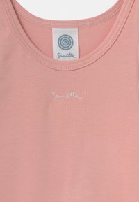 Lys rosa tanktopp laget av mykt, elastisk stoff. Har en rund halslinning og en hvit brodert logo som sier "Sanetta."