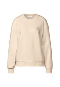 Felpa beige realizzata in morbido materiale, con colletto rotondo e polsini a coste. Un piccolo logo "Quiet Whisper" è ricamato sulla parte anteriore.