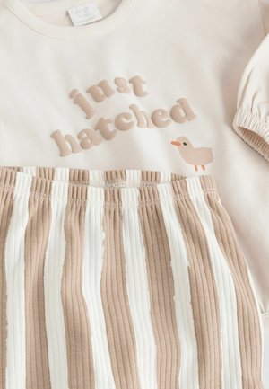 Hellbeiges Kurzarmkleid mit einem gerippten, gestreiften Rock in Beige und Creme, mit dem Schriftzug "just hatched" und einer kleinen Entengrafik.