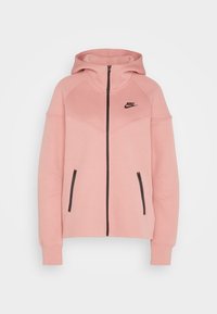 Rosa Kapuzenpullover aus weichem Stoff, mit einem Frontreißverschluss, zwei Reißverschlusstaschen und einem schwarzen Nike-Logo auf der Brust.