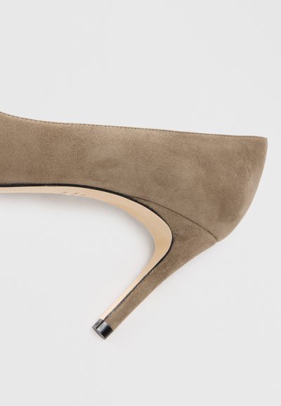 Beige suede high heel shoe with a rounded toe, curved silhouette, and a narrow black accent on the heel's tip.