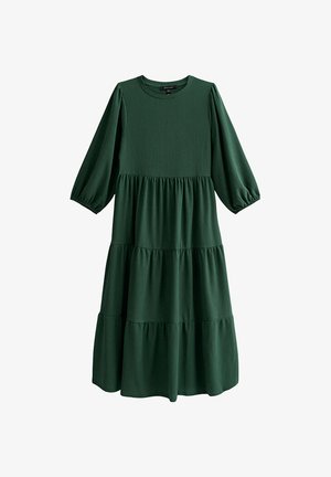 Zielona sukienka warstwowa z rękawami w kształcie balonów do połowy przedramienia, okrągłym dekoltem i prążkowaną fakturą. Wykonana z miękkiego, zwiewnego materiału.