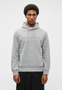 Felpa grigia realizzata in morbido tessuto, con tasca a marsupio anteriore, cordini e logo "Marc O'Polo" in rilievo sul petto.