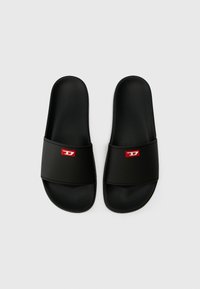 Black slide sandals made of synthetic material. Features a wide band with a red logo accent. Smooth texture, open-toe design, and flat sole.