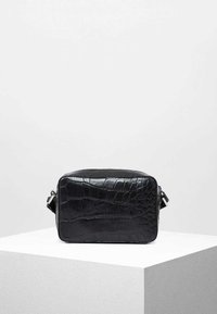 Svart rektangulär crossbody-väska i texturerad konstläder med krokodilsmönster, med avtagbar axelrem och glänsande detaljer.