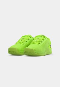 Neonowe zielone buty sportowe z siateczkową cholewką, teksturowanymi detalami i płaskimi podeszwami. Posiadają sznurówki i logo z boku.