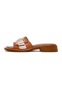Bruine leren slipper met een metallic gouden gesp, platte hak en een smooth ontwerp met een contrasterende lichtbruine band aan de voorkant.