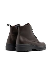 Brązowe skórzane botki za kostkę o gładkiej fakturze, z gumową podeszwą i czarnymi sznurówkami. Z tyłu znajduje się detal z logo marki.