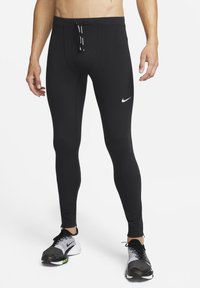 Čierne športové legíny s priliehavým strihom vyrobené z elastického materiálu, s bielym logom Nike a nastaviteľnou šnúrkou v páse.