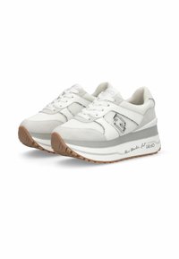 Baskets blanches avec dessus en mesh et suède, semelle en caoutchouc à design épais, et un accent logo argenté sur le côté.