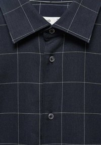 Camicia button-up blu scuro con motivo a quadri bianchi e colletto a punta classico.