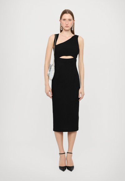 Rochie midi din tricot negru, cu o guleră asimetrică, detalii decupate și o siluetă ajustată. Asortată cu pantofi cu toc ascuțit negri.