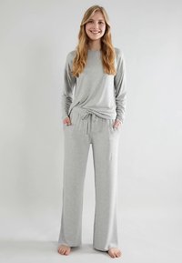 Light gray loungewear set featuring a long-sleeve top with a relaxed fit and drawstring pants, crafted from a soft material.