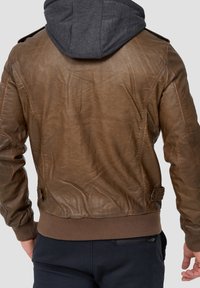 Chaqueta de cuero marrón con capucha gris, acabado texturizado, dobladillo y puños acanalados, costuras detalladas y bolsillo lateral con cremallera.
