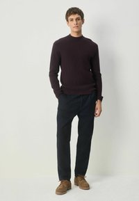 Donkerpaars geribbeld truitje, donkere broek en lichtbruine veterschoenen. Eenvoudig, getailleerd ontwerp met ronde hals. Casual ensemble.