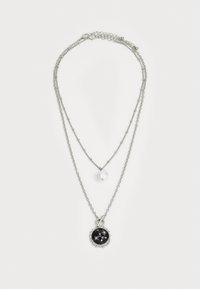 Collier à plusieurs couches en ton argenté, mettant en avant un grand pendentif noir avec des accents argentés et une petite perle blanche sur une chaîne délicate.