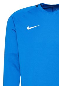 Blå sportig långärmad tröja i mjukt tyg. Har en vit Nike-logotyp på bröstet och svarta detaljer vid halsringningen.