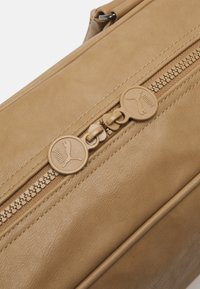 Torebka skórzana w kolorze brązowym z podwójnym zamkiem błyskawicznym z okrągłymi uchwytami z wytłoczonym logo, gładką fakturą i czystym, strukturalnym designem.