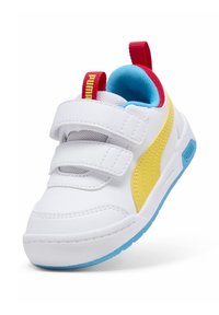 Baskets blanches avec une bande jaune PUMA, des sangles Velcro, et un intérieur bleu. Présentent des accents rouges et une semelle texturée pour une meilleure adhérence.