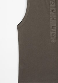 Bezramenný olivově zelený top vyrobený z měkké látky, který má knoflíkovou légu vpředu a rovný, minimalistický design.